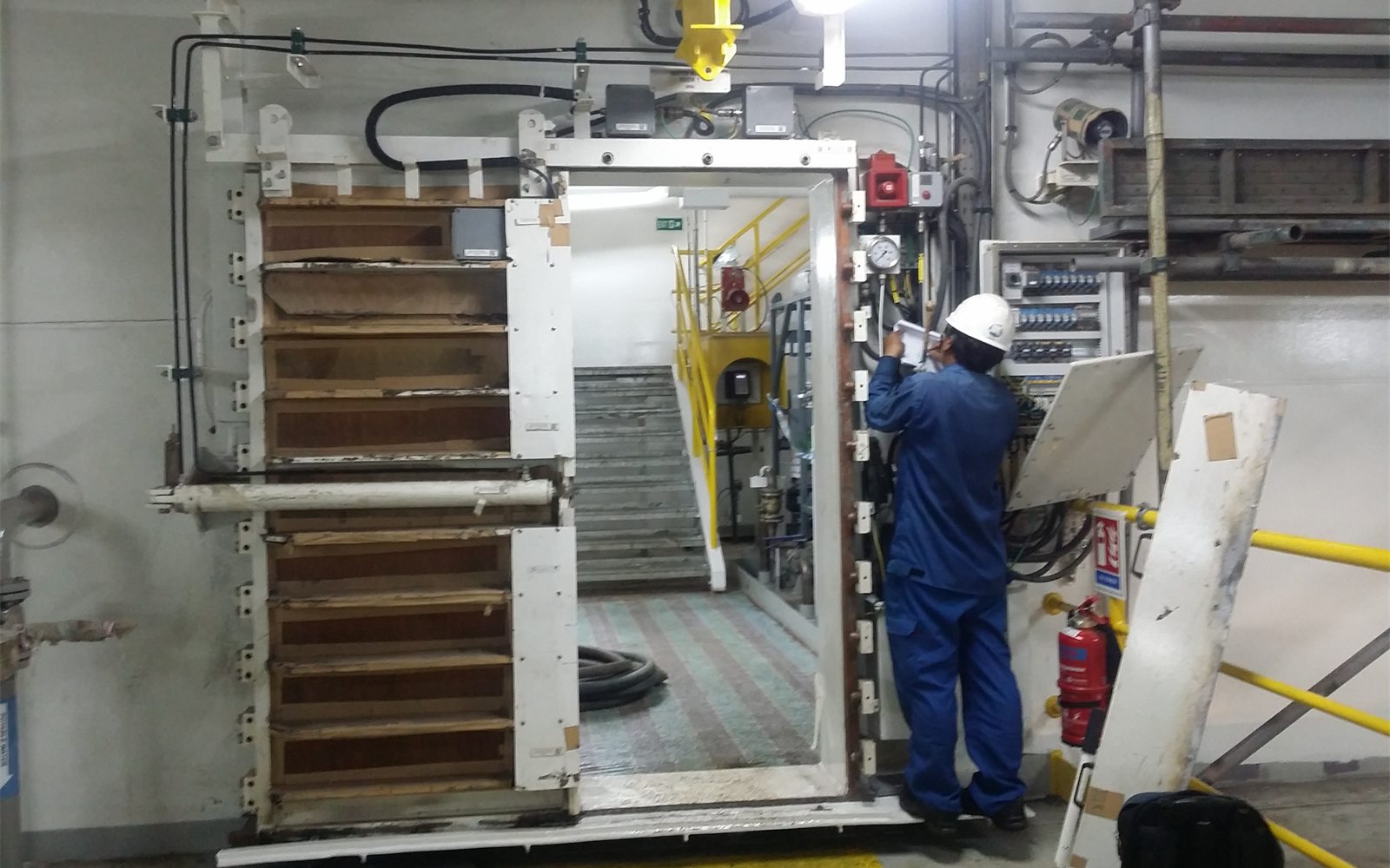 Engineer refurbishing a watertight door on board